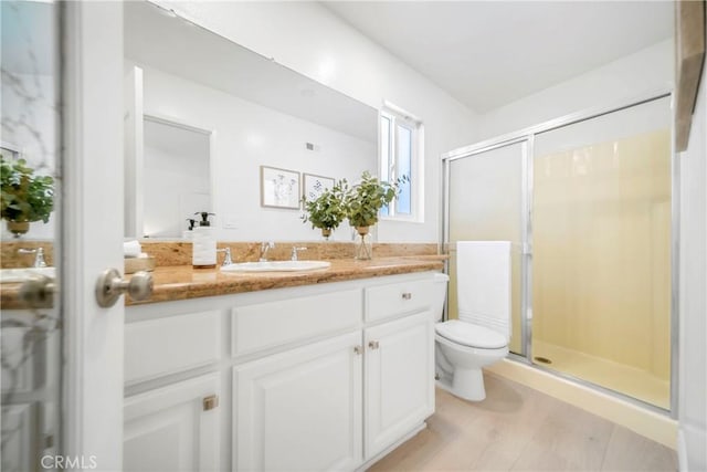 bathroom featuring a shower stall, toilet, and vanity