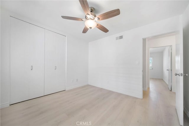 unfurnished bedroom with a closet, visible vents, light wood finished floors, and baseboards