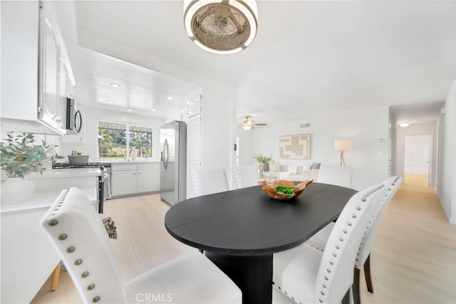 dining space with visible vents, a ceiling fan, and light wood-style floors