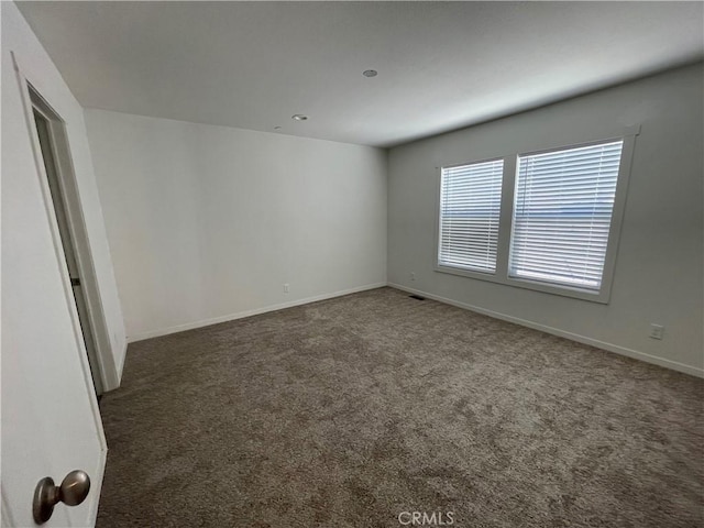 carpeted empty room featuring visible vents and baseboards