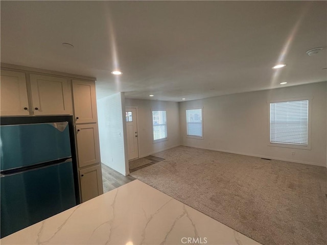 kitchen featuring light stone counters, light carpet, recessed lighting, and freestanding refrigerator