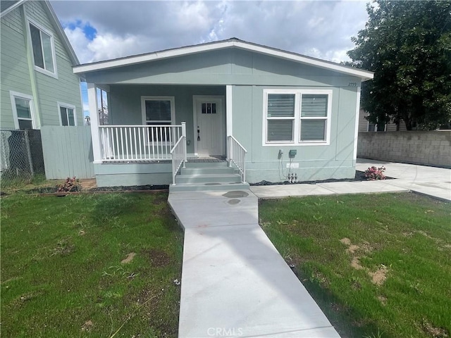 bungalow-style house featuring a front yard, fence, and covered porch