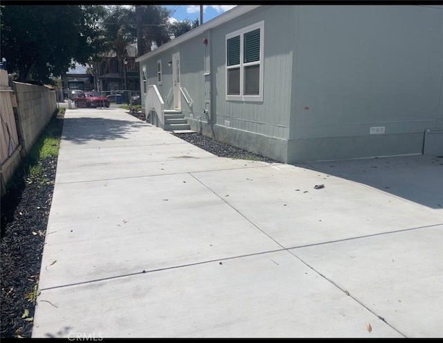 view of side of property featuring concrete driveway, fence, and crawl space