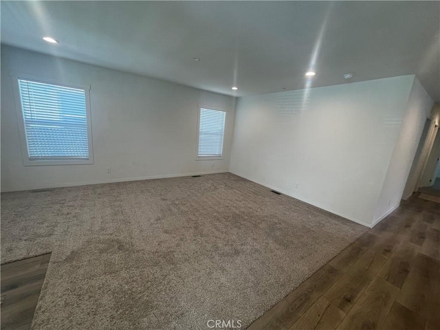 unfurnished room with carpet flooring, recessed lighting, baseboards, and wood finished floors