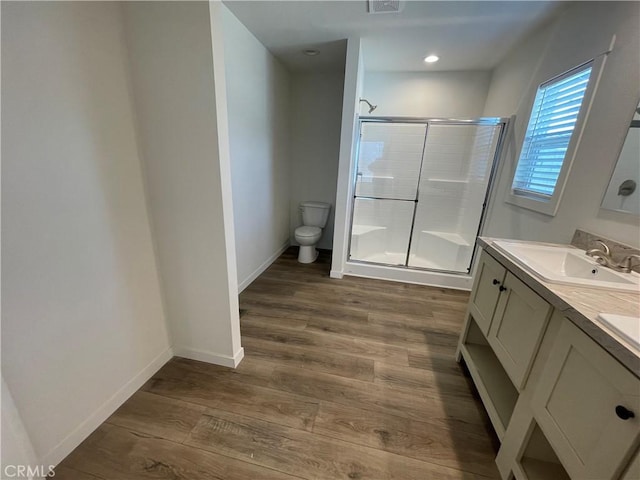 full bath with wood finished floors, baseboards, a sink, a shower stall, and toilet