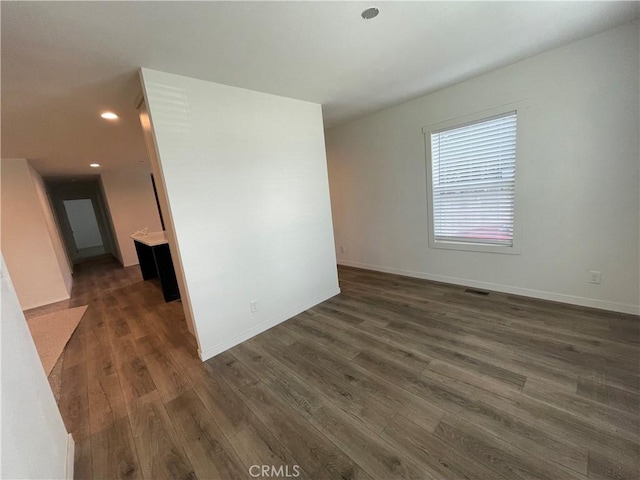 spare room with recessed lighting, baseboards, and dark wood-style floors