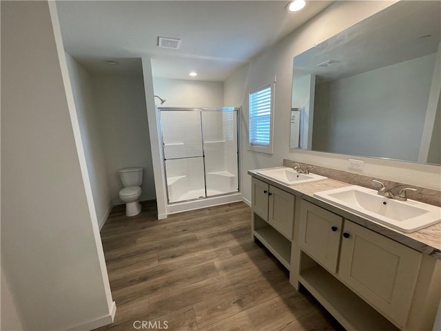 bathroom with a sink, toilet, a stall shower, and wood finished floors