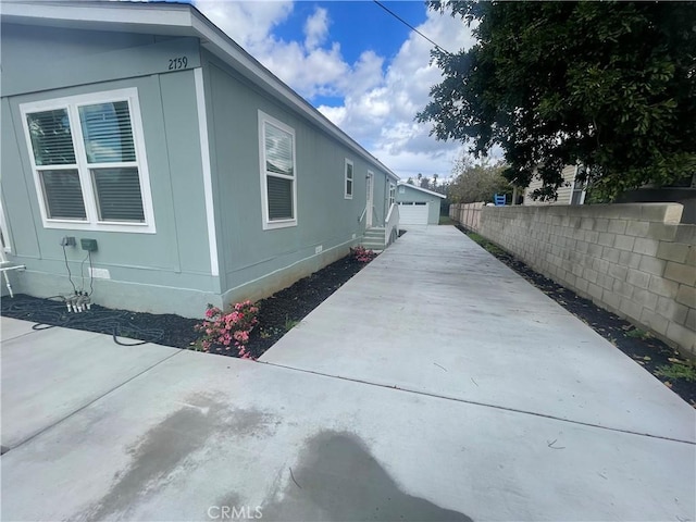 view of side of property featuring an outdoor structure, fence, and crawl space