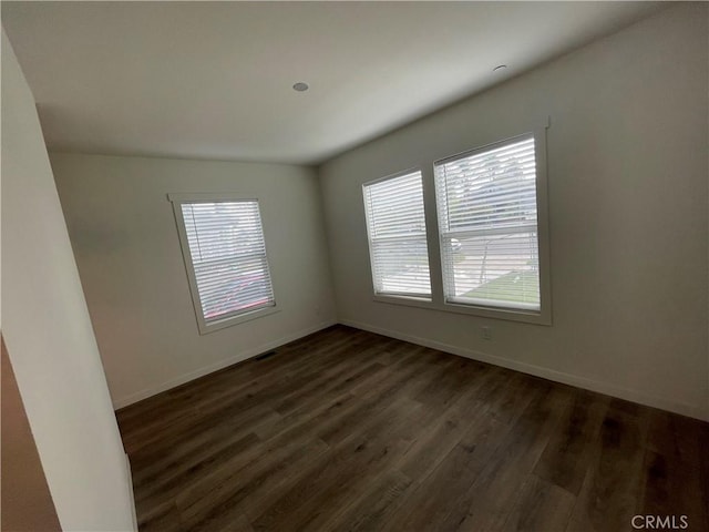 spare room with a healthy amount of sunlight, dark wood-type flooring, and baseboards