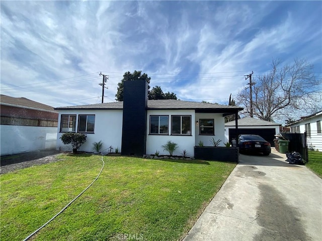 view of front facade featuring stucco siding, driveway, a chimney, and a front yard