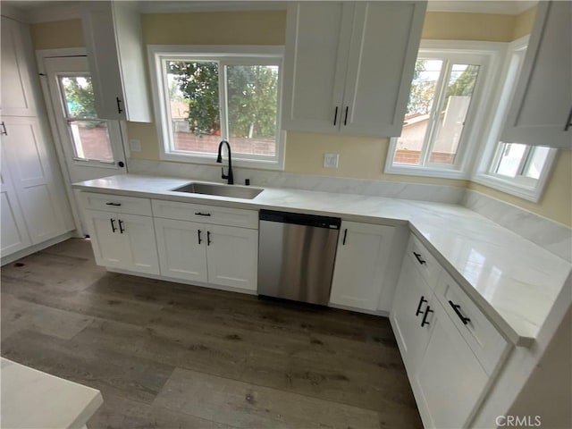 kitchen with light countertops, dark wood-style flooring, stainless steel dishwasher, white cabinetry, and a sink