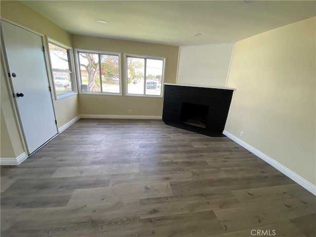 unfurnished living room featuring a fireplace, wood finished floors, and baseboards