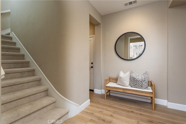 stairs featuring visible vents, baseboards, and wood finished floors