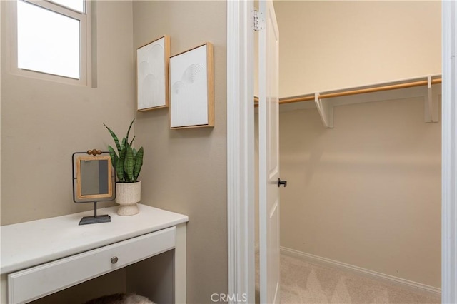 bathroom featuring a walk in closet and baseboards