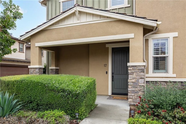 property entrance with stone siding, stucco siding, and board and batten siding