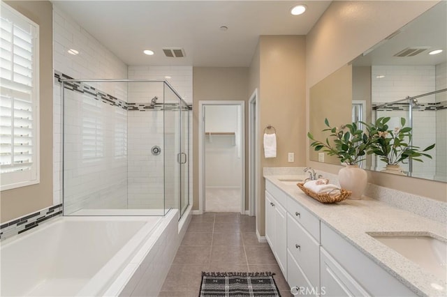 bathroom with visible vents, double vanity, a stall shower, a sink, and a garden tub