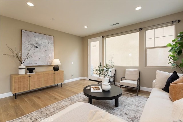 living area with recessed lighting, visible vents, baseboards, and wood finished floors