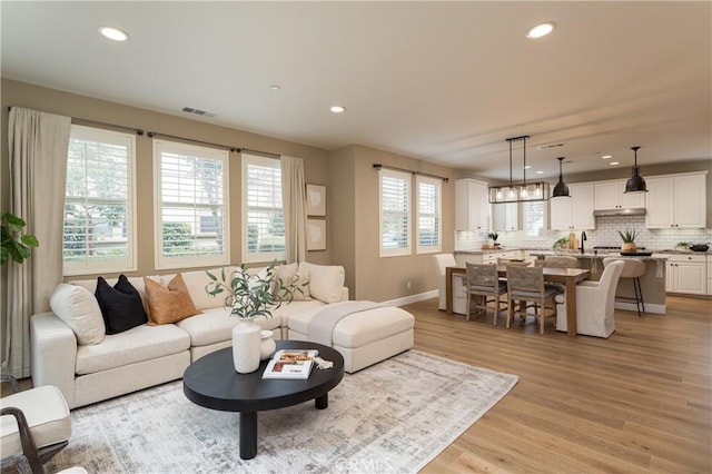 living room with recessed lighting, visible vents, baseboards, and light wood finished floors