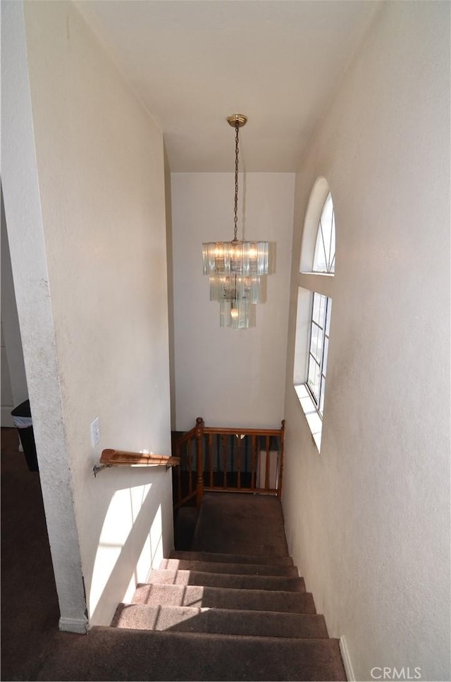 staircase with a notable chandelier