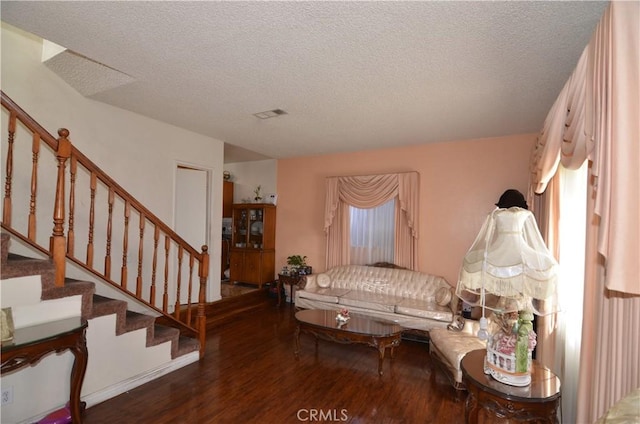 living room with stairway, a textured ceiling, visible vents, and wood finished floors