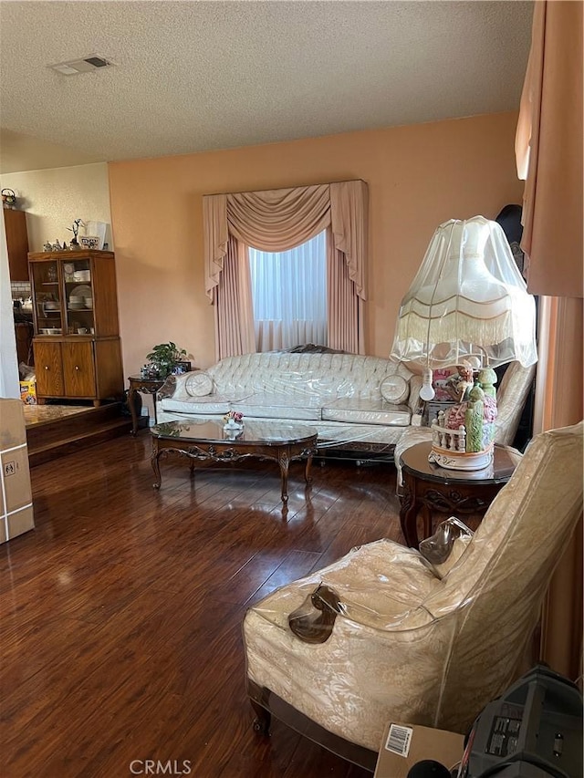 living room featuring visible vents, hardwood / wood-style flooring, and a textured ceiling