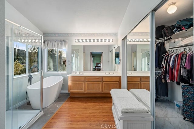 full bath with double vanity, a soaking tub, a spacious closet, and a sink