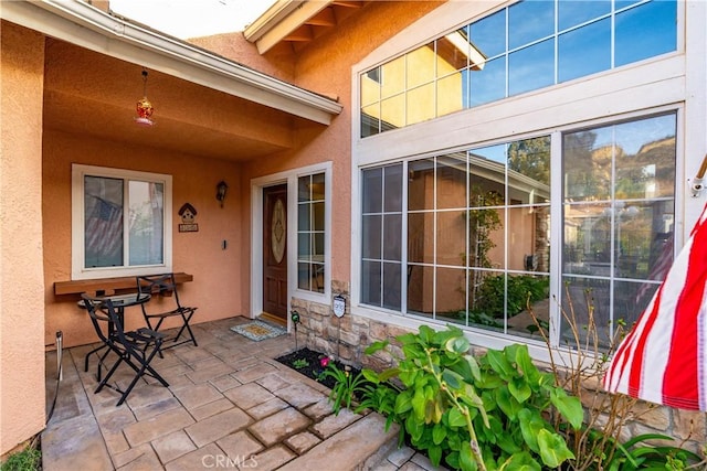 entrance to property featuring stucco siding and stone siding