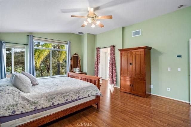 bedroom featuring visible vents, wood finished floors, baseboards, and vaulted ceiling