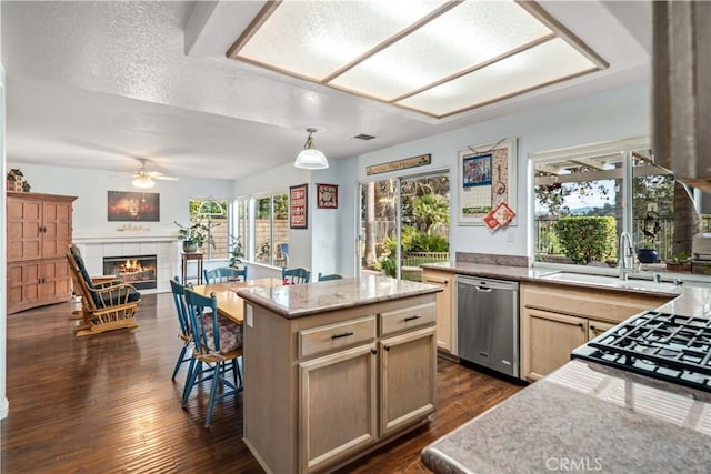 kitchen featuring a sink, a center island, dishwasher, a tile fireplace, and dark wood-style flooring