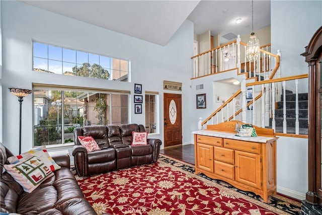 living room featuring a high ceiling, a healthy amount of sunlight, wood finished floors, and stairs