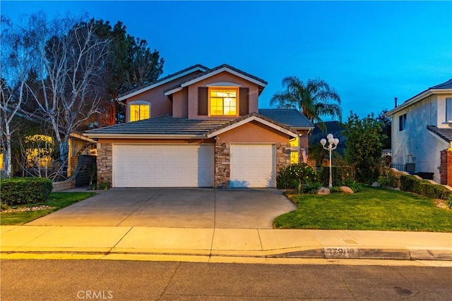 traditional-style house with stone siding, stucco siding, concrete driveway, and a front yard