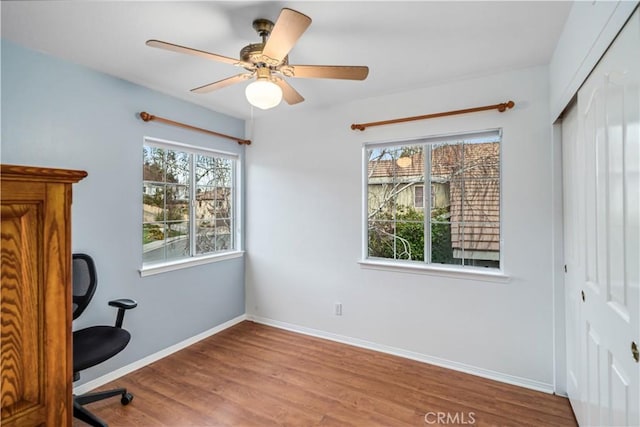 interior space featuring baseboards, wood finished floors, and a ceiling fan