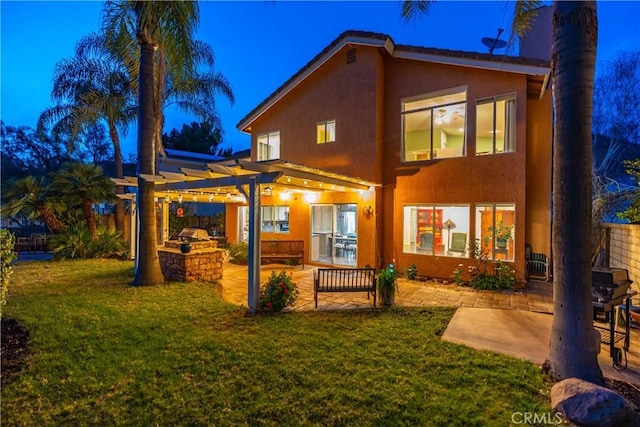 back of property featuring a patio area, a pergola, exterior kitchen, and a yard