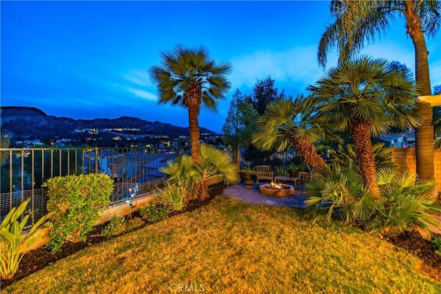 view of yard featuring a patio area, a fire pit, a mountain view, and fence