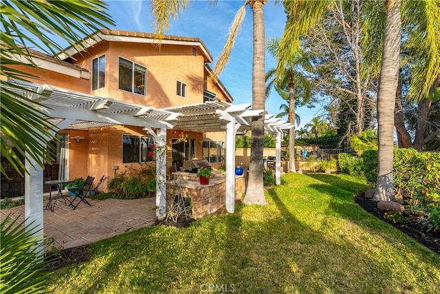 rear view of property with a patio, an outdoor kitchen, a yard, a pergola, and stucco siding