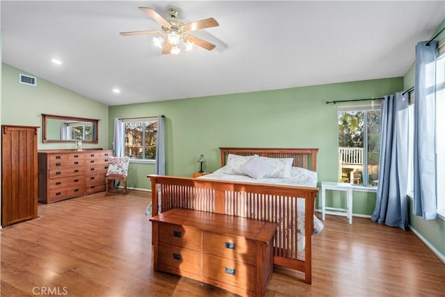 bedroom with visible vents, lofted ceiling, baseboards, and wood finished floors