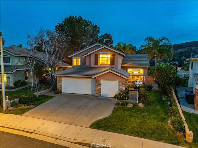 view of front of home with a tiled roof, stone siding, an attached garage, and a front yard