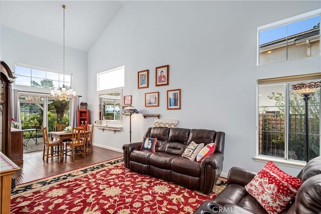 living room featuring baseboards, high vaulted ceiling, an inviting chandelier, and wood finished floors