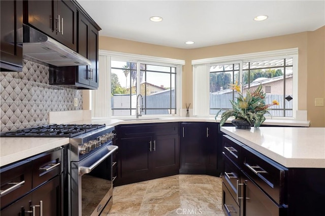 kitchen featuring a sink, a wealth of natural light, under cabinet range hood, and stainless steel stove