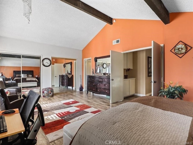 bedroom featuring visible vents, multiple closets, beam ceiling, wood finished floors, and a textured ceiling