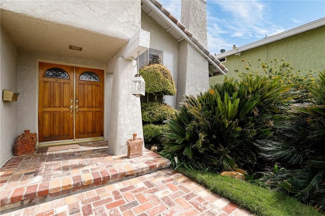 entrance to property featuring stucco siding and a chimney