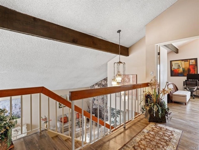 stairs featuring a healthy amount of sunlight, a textured ceiling, vaulted ceiling with beams, and wood finished floors