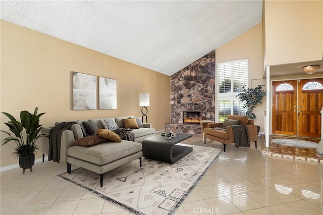 living room featuring high vaulted ceiling, a textured ceiling, a stone fireplace, light tile patterned floors, and baseboards