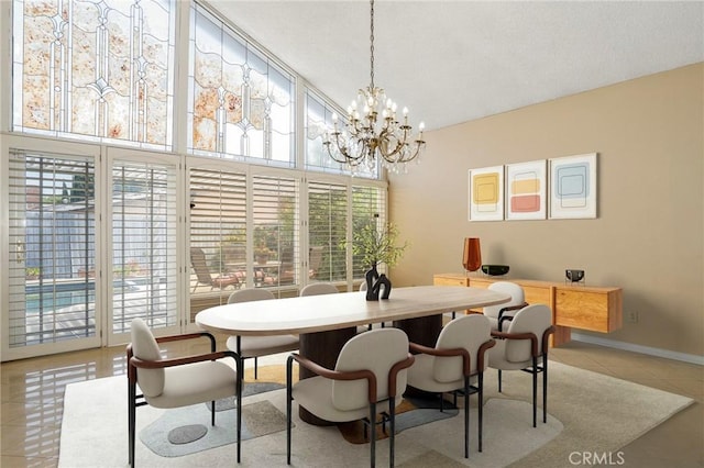 dining space with a high ceiling, light tile patterned floors, baseboards, and a chandelier