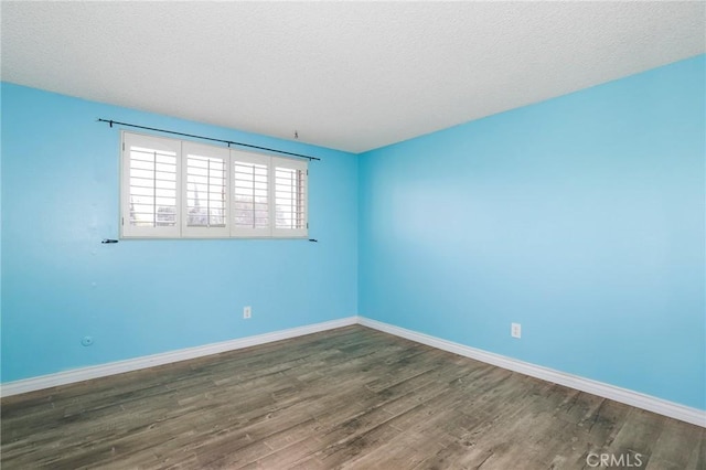 unfurnished room featuring a textured ceiling, baseboards, and wood finished floors