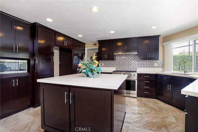 kitchen featuring a sink, under cabinet range hood, tasteful backsplash, appliances with stainless steel finishes, and light countertops