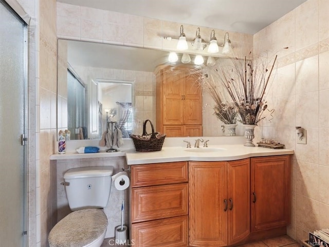 full bath with toilet, vanity, a stall shower, tile patterned floors, and tile walls