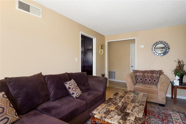 tiled living room with visible vents, a textured ceiling, and baseboards