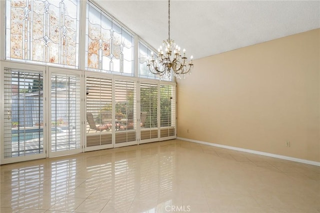 empty room featuring an inviting chandelier, baseboards, tile patterned floors, and a textured ceiling