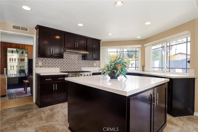 kitchen featuring visible vents, under cabinet range hood, recessed lighting, light countertops, and decorative backsplash